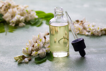 Wall Mural - Robinia (false acacia) essential oil (remedy, extract) bottle with fresh acacia flowers