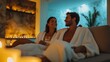 © fotofabrika - A couple enjoying a romantic evening in a candlelit spa setting with cozy robes and drinks in hand