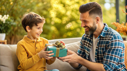 Wall Mural - happy father and son with gift box sitting on sofa in garden at home