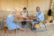 © Evgenij Yulkin/Stocksy - Teenage girl play dominoes with her grandparents in gazebo