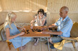 © Evgenij Yulkin/Stocksy - Teenage girl play dominoes with her grandparents in gazebo