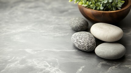 Poster - A serene arrangement of smooth stones beside a wooden bowl with greenery on a textured gray surface