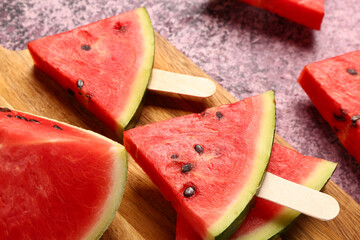 Wooden board with sweet watermelon sticks on purple background