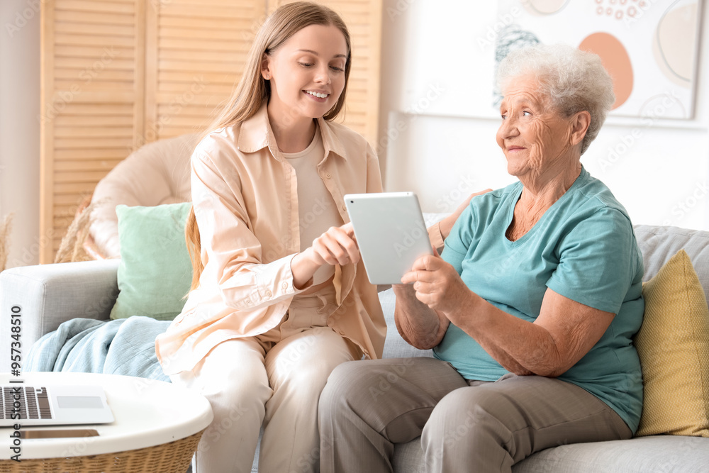 Senior woman with her granddaughter using tablet computer at home