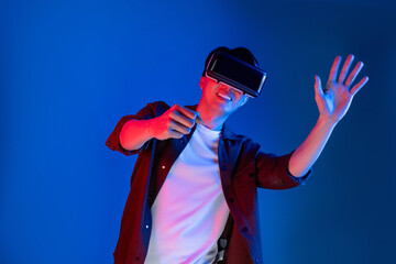 Wall Mural - Smart gamer wearing VR turning to metaverse new world driving in car racing competition game player isolated blue neon light wall connected futuristic technology virtual reality meta. Contrivance.