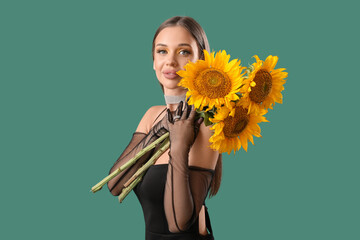 Wall Mural - Elegant young woman with bouquet of beautiful sunflowers on green background