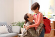 © Pixel-Shot - Military mother hugging and getting her little son ready for school in living room