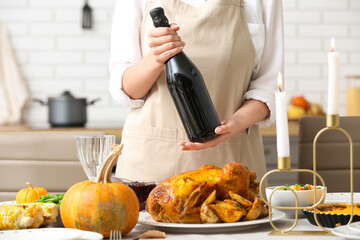 Canvas Print - Woman with bottle of wine at dining table set for Thanksgiving Day, closeup