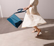 © Ulas&Merve/Stocksy - Graceful Woman in White Dress Holding Blue Leather Handbag