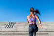 © Nibuya Qubik/Stocksy - A woman in athletic wear running up a set of outdoor concrete stairs