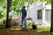 © BONNINSTUDIO/Stocksy - Gardener raking leaves in garden at residential home