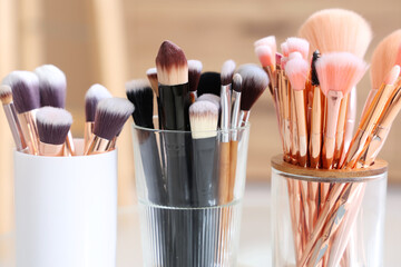 Holders with makeup brushes at home, closeup