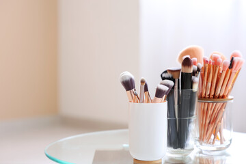 Wall Mural - Holders with makeup brushes on table at home