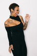 © VICTOR TORRES/Stocksy - Woman in black outfit with tattoos laughing against white background