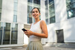 © Miljan Živković - Young woman stand in front company building and use mobile phone