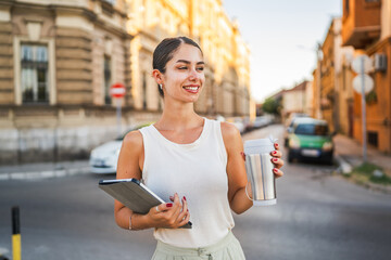 Portrait of young woman stand on the street and use digital tablet