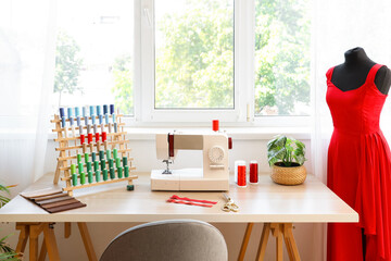 Poster - Tailor's workplace with sewing machine and thread spools in atelier