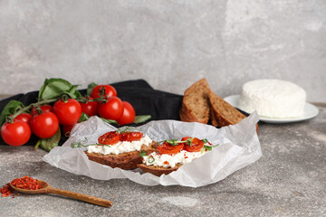 Baking paper of tasty tomato bruschetta with ricotta on grey background