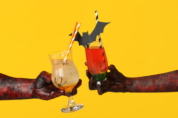 Sticker - Hands of zombies with glasses of cocktails on yellow background. Halloween celebration