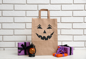 Canvas Print - Paper shopping bag, gifts and lantern for Halloween on table near light brick wall