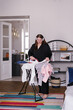 © Oleksii Syrotkin/Stocksy - Plus size woman ironing and listening to podcast in headphones