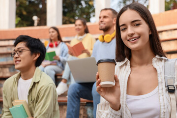 Canvas Print - Female student with coffee cup having lecture outdoors, closeup