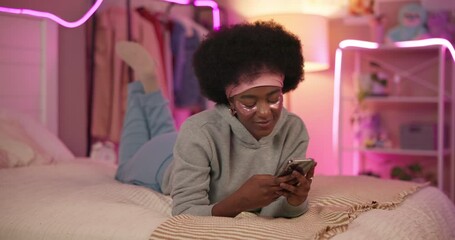 Poster - Home, typing and black woman with cellphone, bed and social media with message, internet and relax. African person, apartment and girl with smartphone, smile and online chatting with mobile user