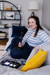 © Oleksii Syrotkin/Stocksy - Young podcaster smiling to camera while sitting cross-legged on sofa