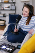 © Oleksii Syrotkin/Stocksy - Plus size podcaster in headphones recording content sitting on sofa