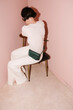 © Ulas&Merve/Stocksy - Contemplative Woman Sitting on Chair Against Pink Background