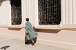 © Ulas&Merve/Stocksy - Person Walking Outdoors Carrying Bag Near Historic Building