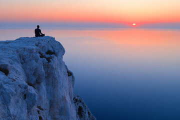 Poster - A man is sitting on a rock overlooking the ocean