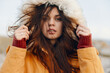 © SHOTPRIME STUDIO - Woman in yellow coat with windblown hair standing by ocean, travel and beauty concept
