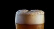 © Ben Kuang - Close-up of a frothy beer glass with bubbles against a black background.