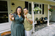 © Serena Burroughs/Stocksy - smiling lgbtq couple taking selfie with key and new house