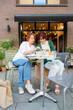 © Danil Nevsky/Stocksy - Women Looking at Phone at Outdoor Cafe