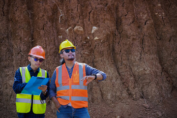 two young male construction workers are surveying using blueprints in the field