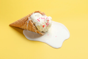 Canvas Print - Melted ice cream in wafer cone on yellow background