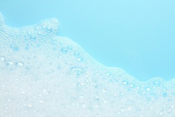 Poster - Washing laundry. White foam with bubbles on light blue background, top view