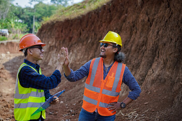 Two construction workers high-five, give thumbs up and shake hands because they have agreed to the work.