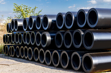 A stack of large diameter black plastic PVC pipe for a water main project