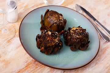 Sticker - Delicious dish of Mediterranean cuisine is appetizing artichokes on a plate, sprinkled with salt on top