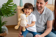 © mahalo studio/Stocksy - girl holding stuffed animal smiling with family at home
