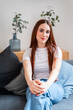 © mahalo studio/Stocksy - redhead woman smiling while sitting on a sofa