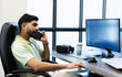 © Wavebreak Media - Talking on phone, Indian man working at desk with computer and VR headset