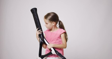 Wall Mural - Young happy female tennis player with big oversize racket. Girl posing in pink sports outfit and bouncing a ball in her hand. Failed attempt with angry face expression.