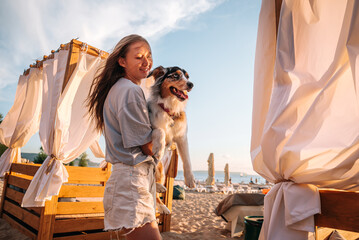 beautiful girl and smart cheerful funny tricolor dog Australian Shepherd on the surf beach relaxing hugging playing having fun and fooling around the dog shows tricks