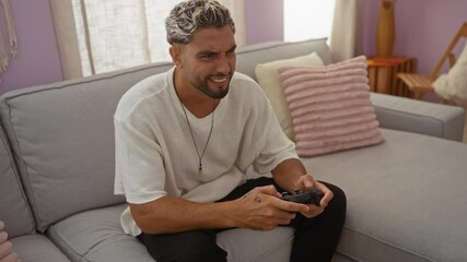 Sticker - Young man with beard playing video game indoors on gray sofa in cozy living room home setting