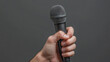 © Sahraya - Man’s hand holding a microphone on a blue background.