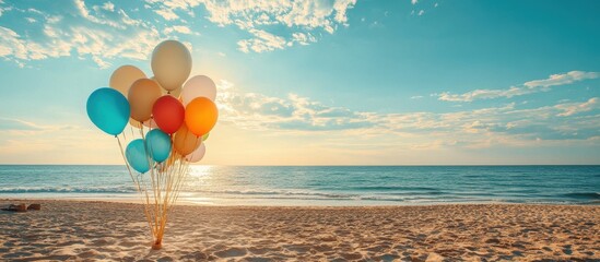 Wall Mural - Colorful Balloons on a Sandy Beach at Sunset with a Calm Ocean and Cloudy Sky in the Background